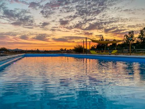 una piscina con puesta de sol en el fondo en Cabaña con piscina, en Peralillo