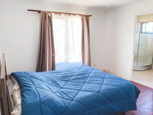 niebieskie łóżko w pokoju z oknem w obiekcie Cabaña con piscina w mieście Peralillo