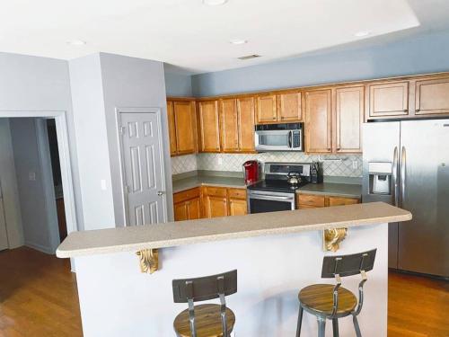 a kitchen with wooden cabinets and a counter with two bar stools at Entire Home Downtown ATL! Walk to GWCC and more! in Atlanta