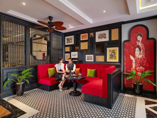 順化的住宿－色調寧靜皇宮酒店，两人坐在一个房间里红色的沙发上