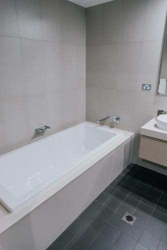 a white bathroom with a tub and a sink at Novotel Newcastle Beach in Newcastle