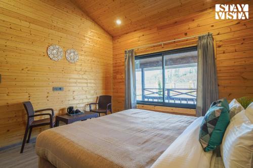 Un dormitorio con una cama grande y una ventana en StayVista at Secret Solace en Dehradun