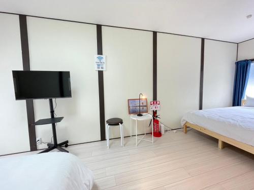 a bedroom with a bed and a flat screen tv at A&C House 新大阪 in Osaka