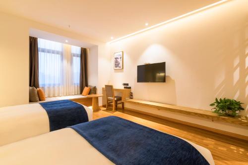 um quarto de hotel com duas camas e uma televisão de ecrã plano em Supu Hotel - Zhengzhou CBD International Convention and Exhibition Center em Zhengzhou