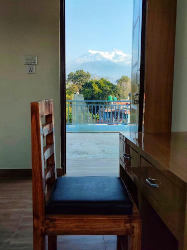 a wooden chair sitting at a desk with a window at Fewa Apartment in Pokhara