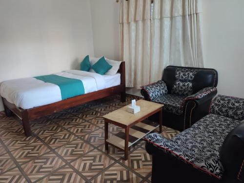 a room with a bed and two chairs and a table at Fewa Apartment in Pokhara