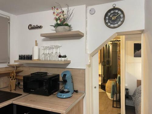 eine Küche mit einer Mikrowelle und einer Uhr an der Wand in der Unterkunft Appartement place de Cambrai in Cambrai