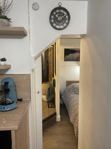 Cette chambre comprend un lit et une horloge murale. dans l'établissement Appartement place de Cambrai, à Cambrai