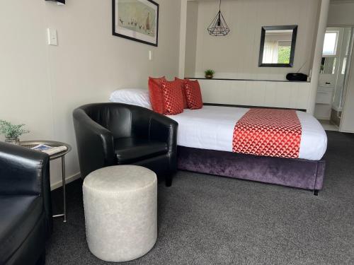 ein Hotelzimmer mit einem Bett, einem Stuhl und einem Stuhl in der Unterkunft Golden Leaf Apartments in Invercargill