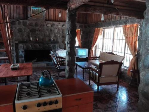 a kitchen with a stove and a living room at Cabañas El Remanso in Linares