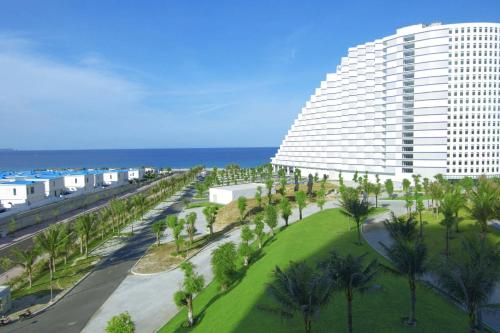 een groot gebouw met palmbomen voor de oceaan bij Seaview Hotel - Arena Cam Ranh Resort in Cam Ranh