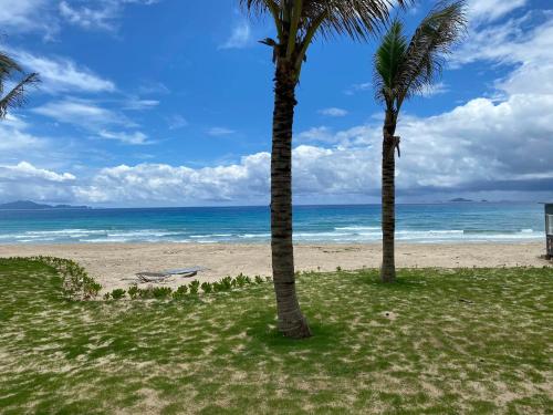 two palm trees on a beach with the ocean at Seaview Hotel - Arena Cam Ranh Resort in Cam Ranh