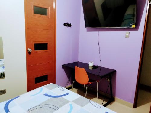 Habitación con mesa, cama y TV. en HOSTAL TOSCANO SUITES, en El Tambo