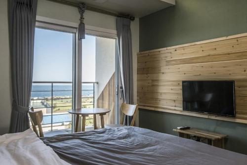 um quarto com uma cama e uma televisão de ecrã plano em Handongijen Pension em Jeju