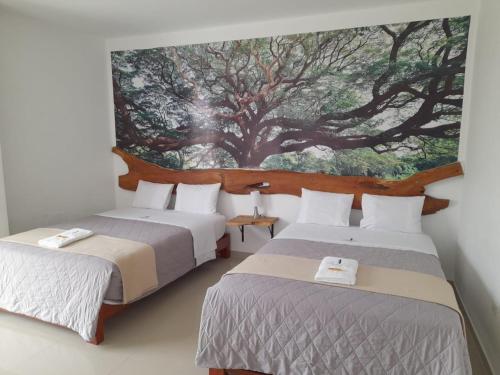 two beds in a room with a painting on the wall at CasaBlanca Hotel in Huambo