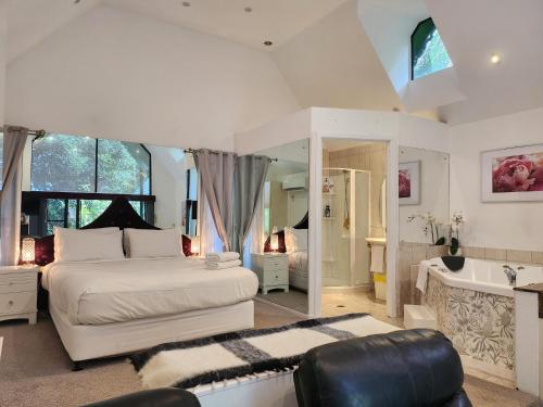 Gallery Walk Chalets - Tamborine Mountain في جبل تامبورين: غرفة نوم مع سرير وحوض استحمام ومغسلة