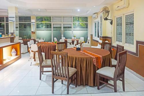 un comedor con mesas, sillas y ventanas en COLLECTION O 91331 Hotel Grand Saota Soppeng, en Watansopeng