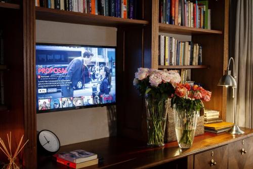 two vases with flowers on a table in front of a tv at The Great Gatsby Houghton in Johannesburg