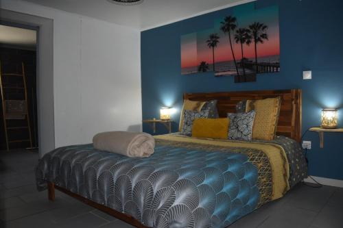 a bedroom with a bed with blue walls and palm trees at Au Coeur des hauts Cilaos in Cilaos