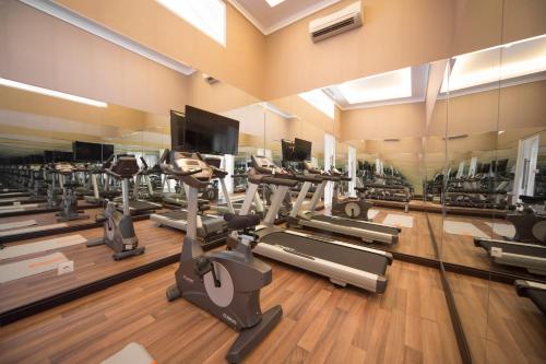 a gym with a lot of treadmills and machines at Maison Aurelia Sanur, Bali - By Préférence in Sanur