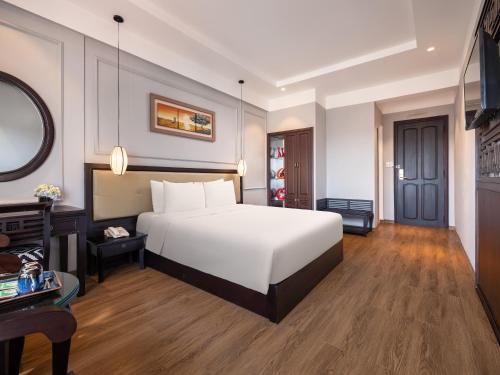 a bedroom with a white bed and a desk at Hue Serene Palace Hotel in Hue