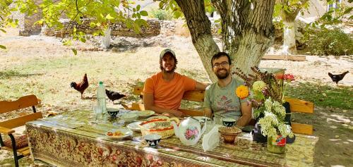 a man and a woman sitting at a table at Kuldosh`s homestay in Majrum village in Madzherum