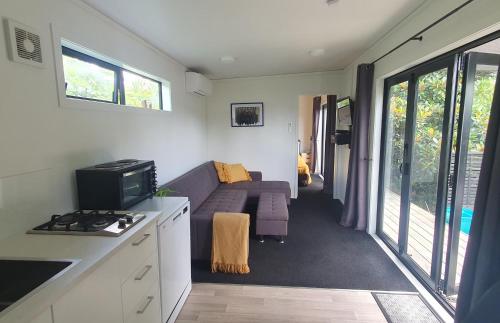 a small living room with a couch and a tv at Private Cabin in Waihi