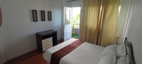 a white bedroom with a bed and a window at Cozzy 24 in Maputo