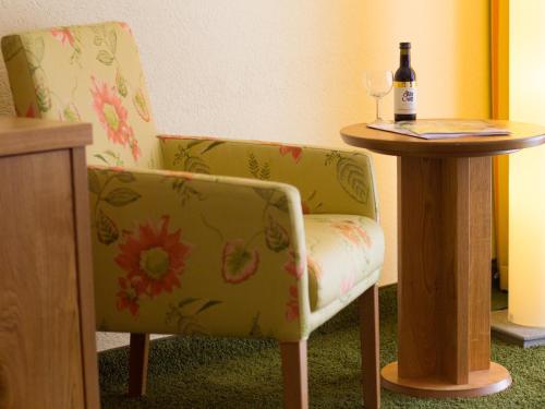 a chair sitting next to a table with a bottle of wine at Ringhotel Mönch`s Waldhotel in Unterreichenbach