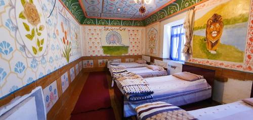 a row of beds in a room withpainted walls at Kuldosh`s homestay in Majrum village in Madzherum