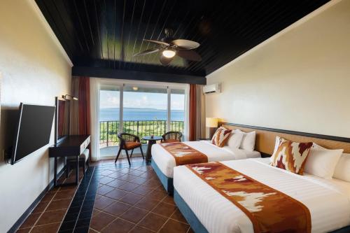 a hotel room with two beds and a balcony at Coral Ocean Resort in Saipan
