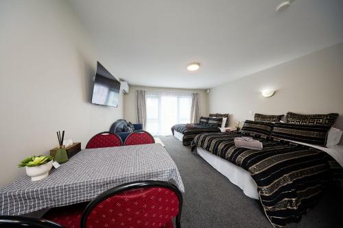 a room with four beds and chairs and a television at Willowbank Motel in Kaikoura