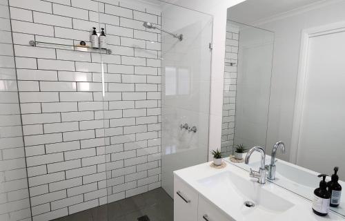 a white bathroom with a sink and a shower at Seaside Aura in Victor Harbor