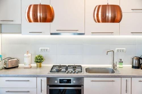a kitchen with white cabinets and a sink at Modern Apollus Avenue - By OpenHouse apartments in Timişoara