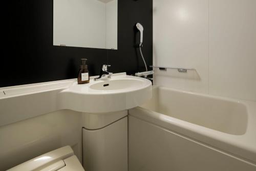 a white bathroom with a sink and a bath tub at the b osaka-shinsekai in Osaka