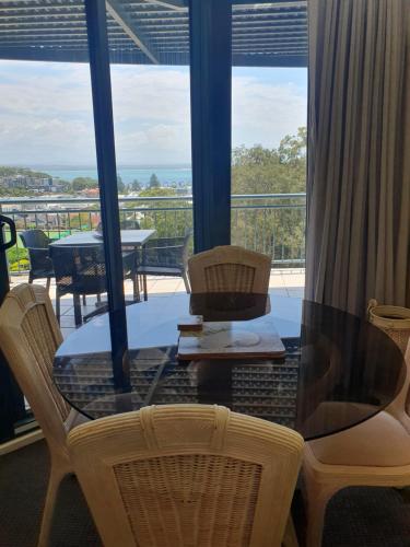 a glass table and chairs with a view of a balcony at Casablanca Penthouse Loft - Landmark 518 in Nelson Bay