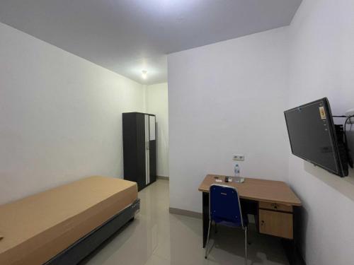 Zimmer mit einem Bett, einem Schreibtisch und einem TV in der Unterkunft OYO 93297 Penginapan Musafir Syariah in Pangkajene