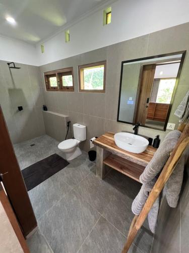 ein Badezimmer mit einem Waschbecken, einem WC und einem Spiegel in der Unterkunft Blamada Villas in Sekongkang