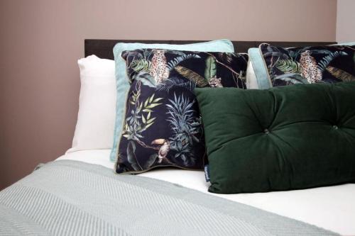 una pila de almohadas encima de la cama en Free Wifi | Parking Access | 3BR, en Rogerstone
