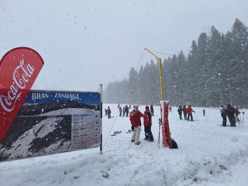 a group of people in the snow next to a cocacola sign at Pensiunea Sarah Bran in Bran