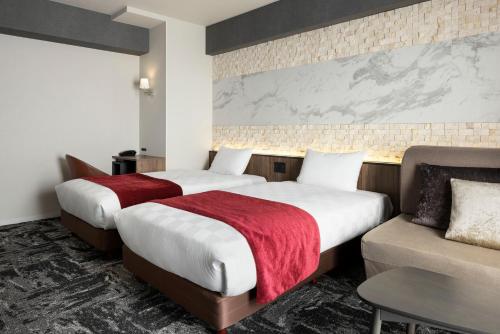 ein Hotelzimmer mit 2 Betten und einem Sofa in der Unterkunft the b osaka-shinsekai in Osaka