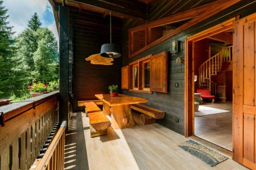 a porch of a log cabin with a wooden table and bench at Chalet Soleada - Happy Rentals 
