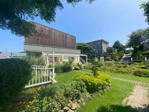 a house with a barn on top of a garden at PREERIA Pension in JEJU in Jeju