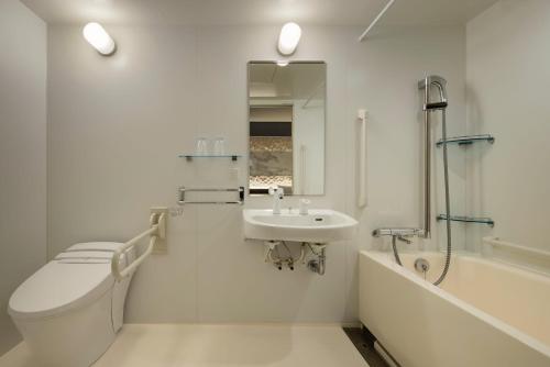a white bathroom with a toilet and a sink at the b osaka-shinsekai in Osaka
