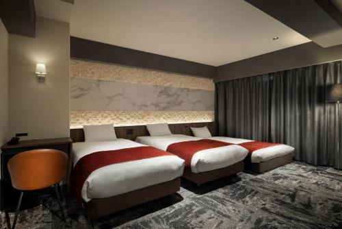 une chambre d'hôtel avec deux lits et une chaise dans l'établissement the b osaka-shinsekai, à Osaka