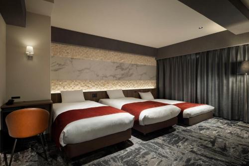 a hotel room with two beds and a chair at the b osaka-shinsekai in Osaka