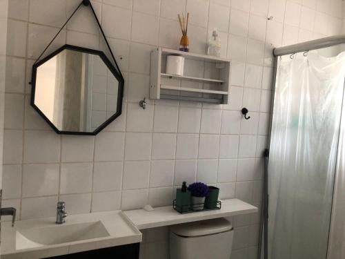 uma casa de banho com um lavatório, um espelho e um WC. em Apartamento Belas Artes Itanhaém em Itanhaém