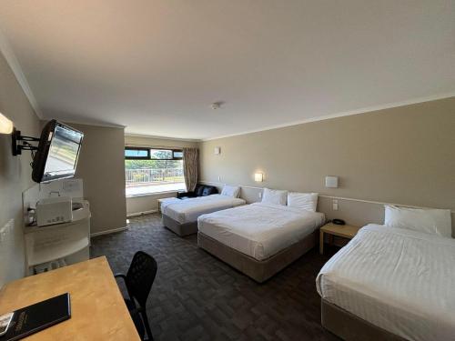 ein Hotelzimmer mit 2 Betten und einem Tisch in der Unterkunft Geraldton Motor Inn in Geraldton