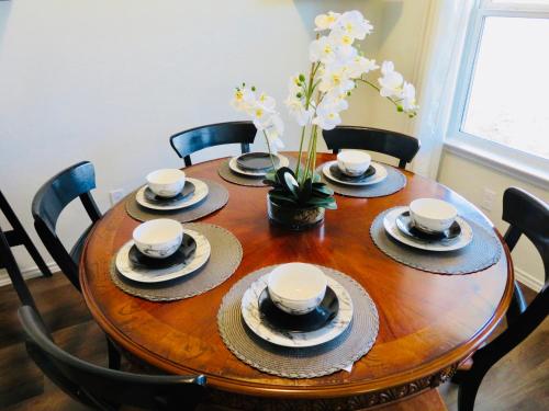 a wooden table with plates and cups and a vase with flowers at New House family friendly near Six Flags Sea World in Helotes