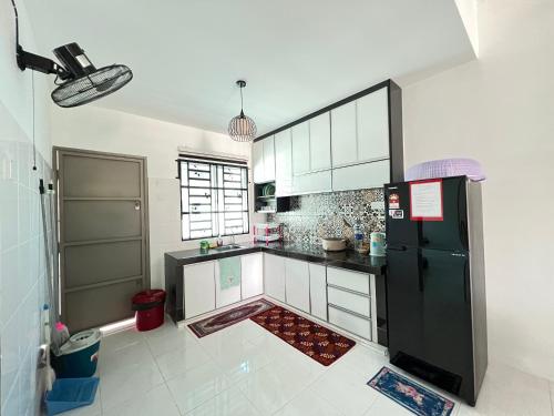 a kitchen with a black refrigerator and white cabinets at Chempaka Homestay (Near to UTP UiTM Seri Iskandar) in Seri Iskandar